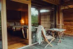 cozy wooden porch with a table and chairs, light from inside