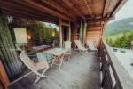 wooden deck with chairs and tables surrounded by greenery