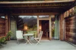 wooden deck with two chairs and a small table, surrounded by greenery