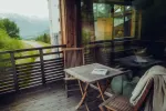 Cozy wooden balcony with a table, chairs, and a view of nature