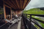 Wooden balcony with lounge chairs overlooking green hills