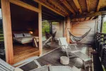 Wooden terrace with hammocks, lounge chairs, and a bedroom visible inside.