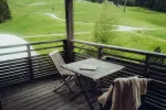 Wooden balcony with a table and chair overlooking green fields