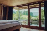 Modern bedroom with large windows overlooking a green landscape