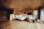 stylish bedroom with wooden floor, bed, couch, and floor lamp