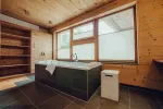 modern bathroom with bathtub, window, and wooden shelves