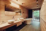modern bathroom with wooden walls, double sinks, and a freestanding bathtub