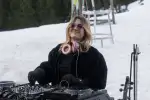 DJ in black jacket on snow with headphones