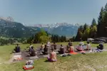 Group sitting on grass with mountains in the background