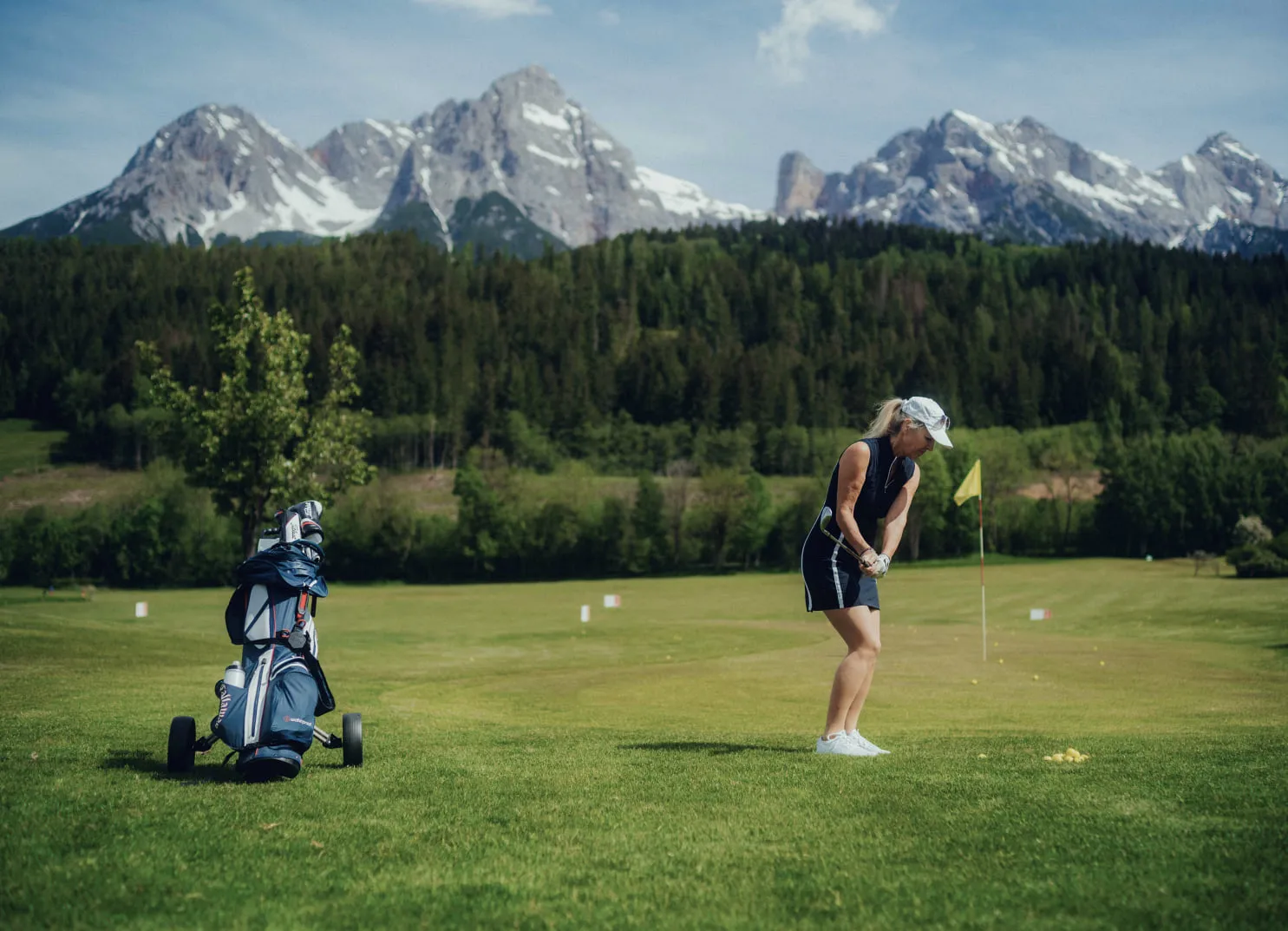 Frau spielt Golf vor Bergkulisse