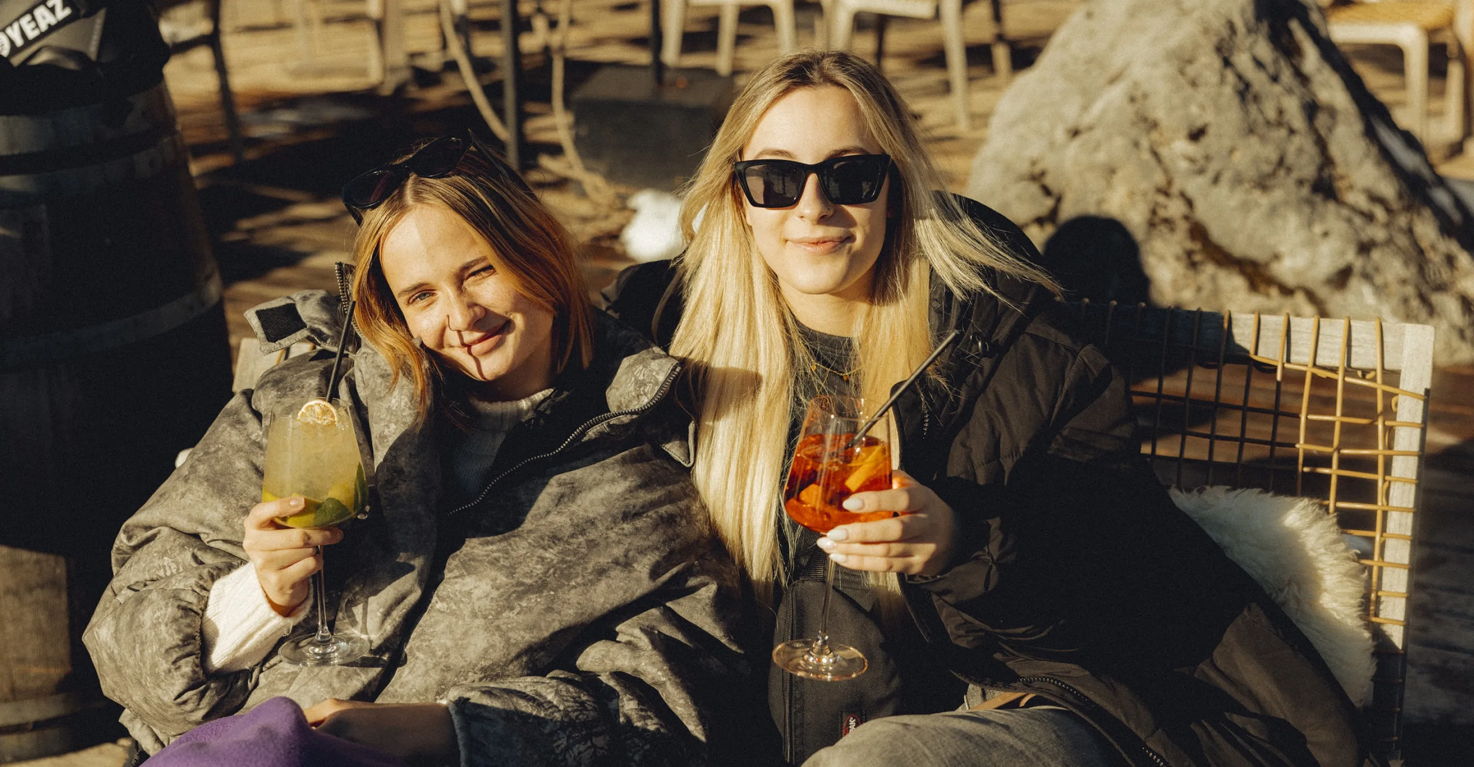 Zwei Frauen stoßen mit bunten Cocktails an