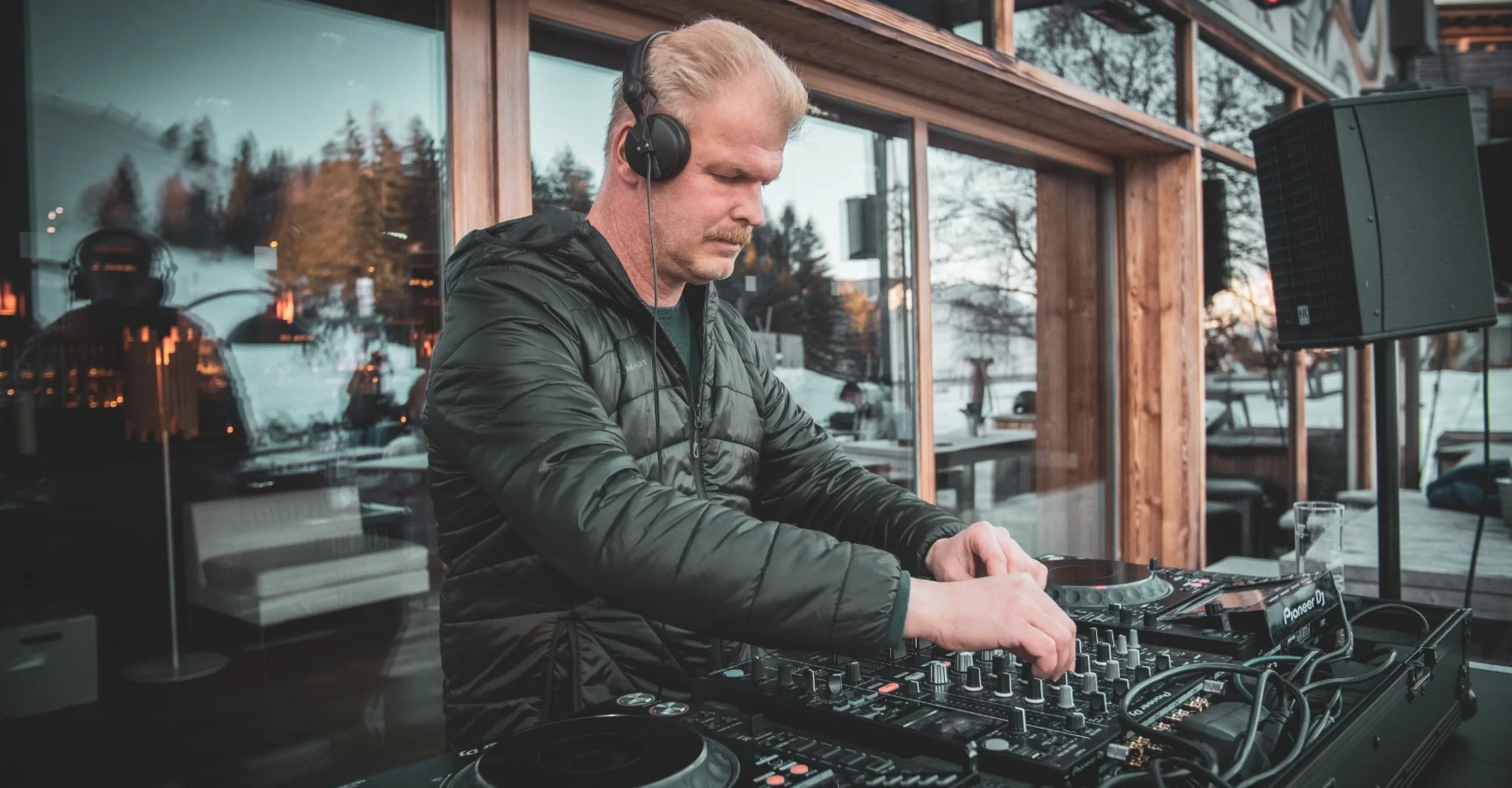 DJ at a mixing console in Jo Forsthofalm, modern setting.