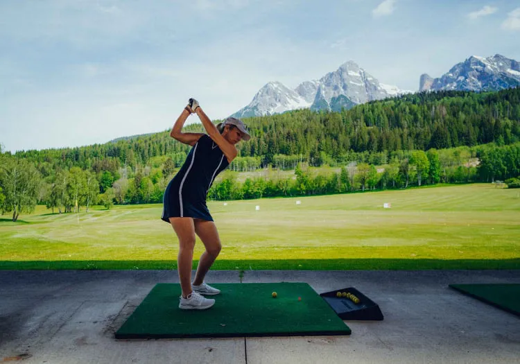 Frau spielt Golf vor Bergkulisse