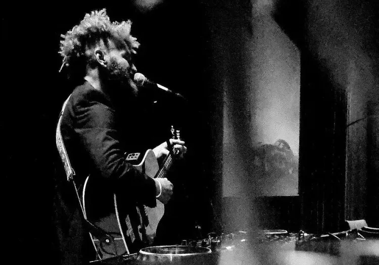 Musician performing with an acoustic guitar on stage