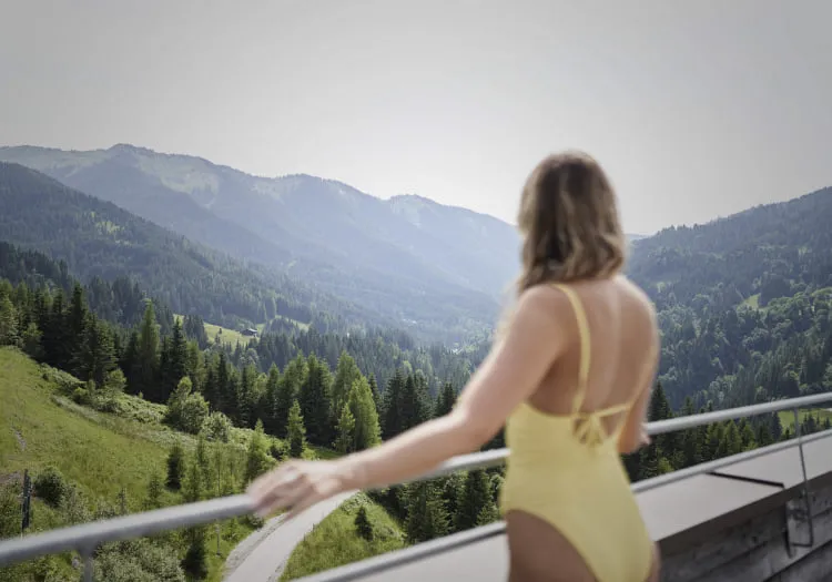 Frau in gelbem Badeanzug am Balkon mit Bergblick