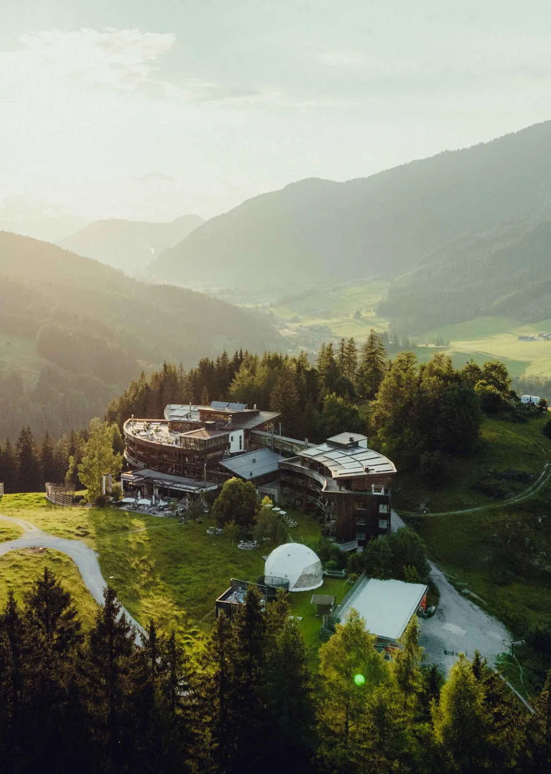 Holzhotel Forsthofalm in den Bergen, umgeben von Wäldern und Wiesen.
