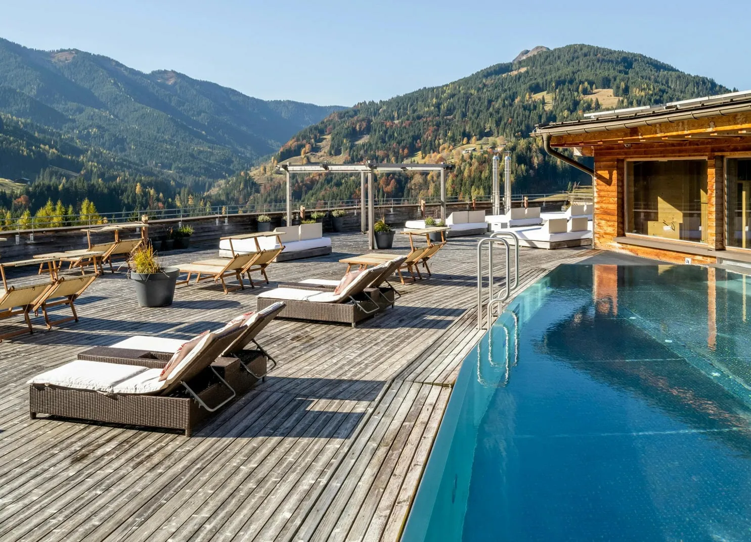 Wooden deck with lounge chairs and swimming pool overlooking mountains